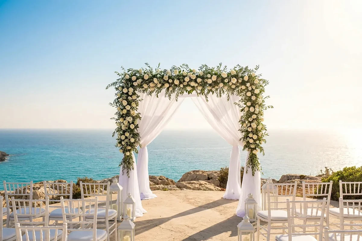 Ceremonie de mariage a l'etranger sur une falaise face a la mer, arche fleurie blanche