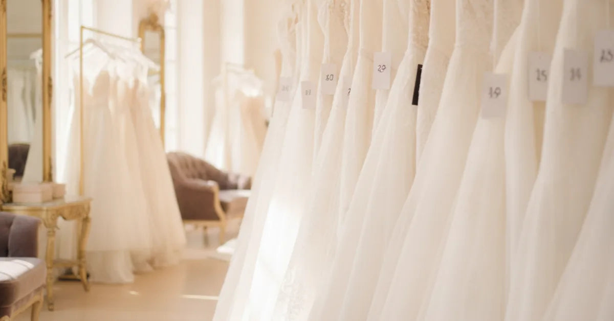 Robes de mariée alignées sur un portant de boutique avec étiquettes de prix
