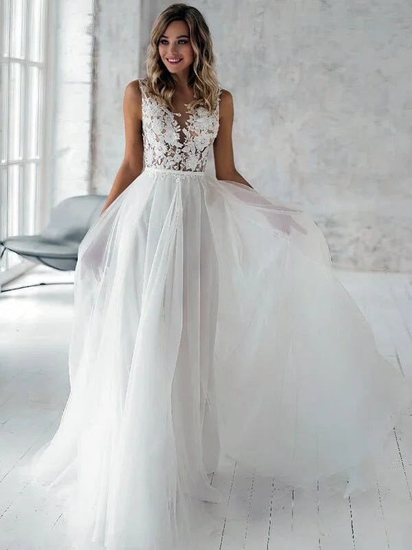 Robe de mariée moderne blanche en tulle fluide avec bustier en dentelle florale sans manches, décolleté illusion et jupe aérienne, style élégant et contemporain.