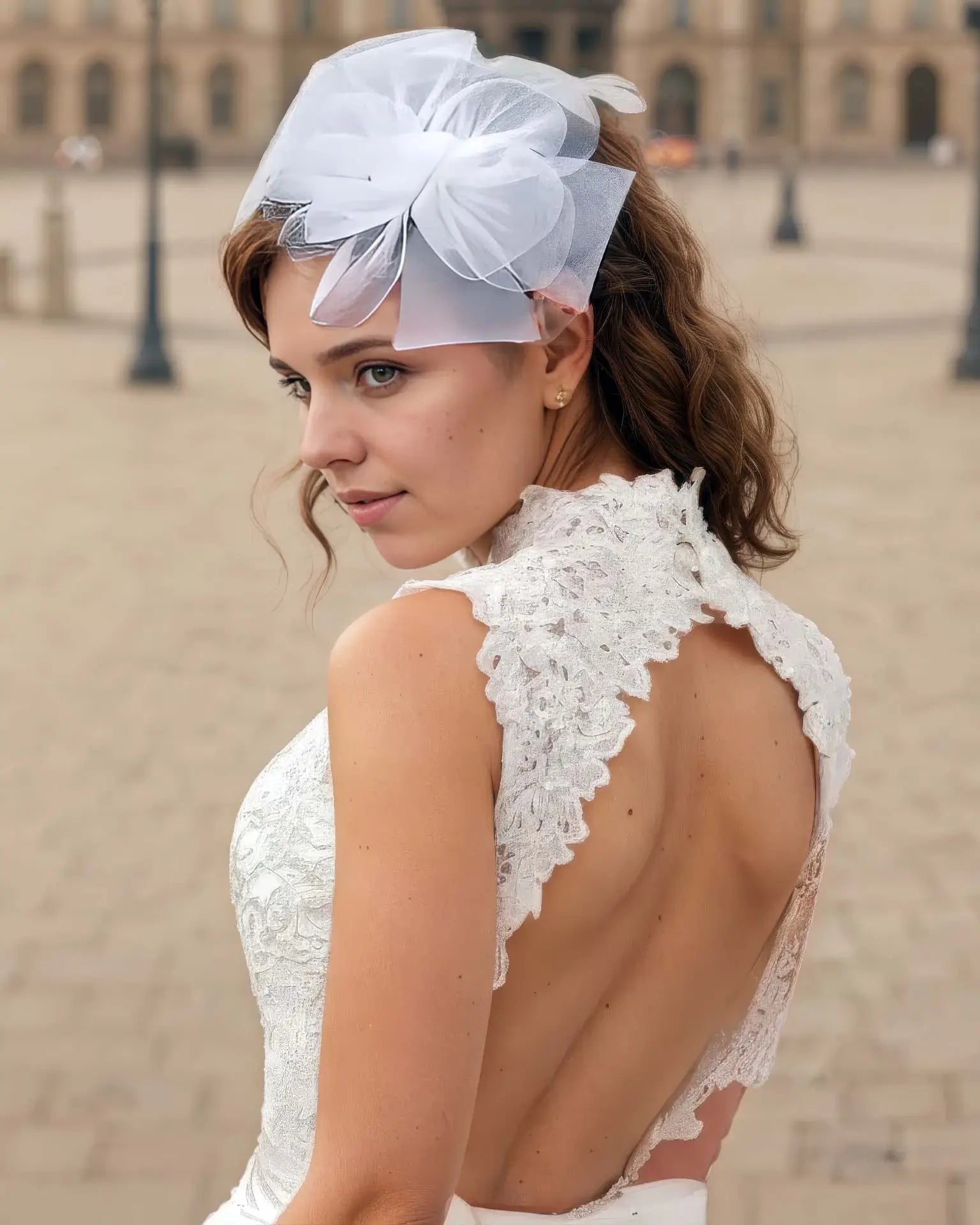 Dos nu en dentelle de la robe de mariée courte vintage, avec coiffe blanche élégante, photographié en extérieur à Paris.