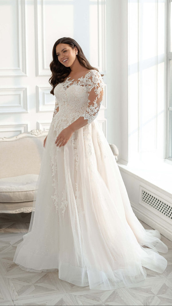 Robe de mariée champêtre femme ronde, manches 3/4 et décolleté illusion en dentelle florale, jupe évasée en tulle pailleté
