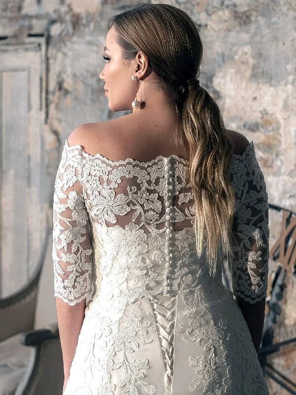 Robe de mariée romance grande taille vue dos en dentelle florale avec épaules dénudées, manches mi-longues transparentes et fermeture boutonnée, silhouette élégante et féminine.