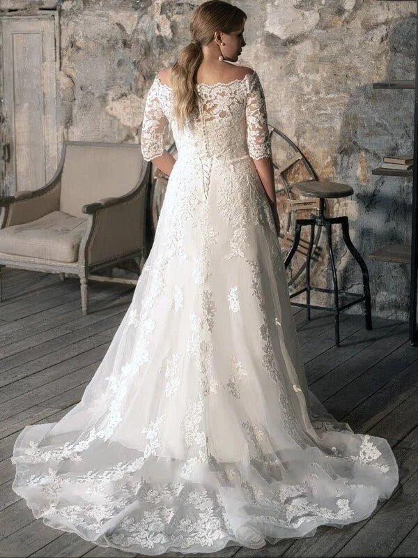 Robe de mariée romance grande taille en dentelle avec coupe évasée, manches mi-longues et jupe fluide avec traîne, style romantique et raffiné en intérieur.
