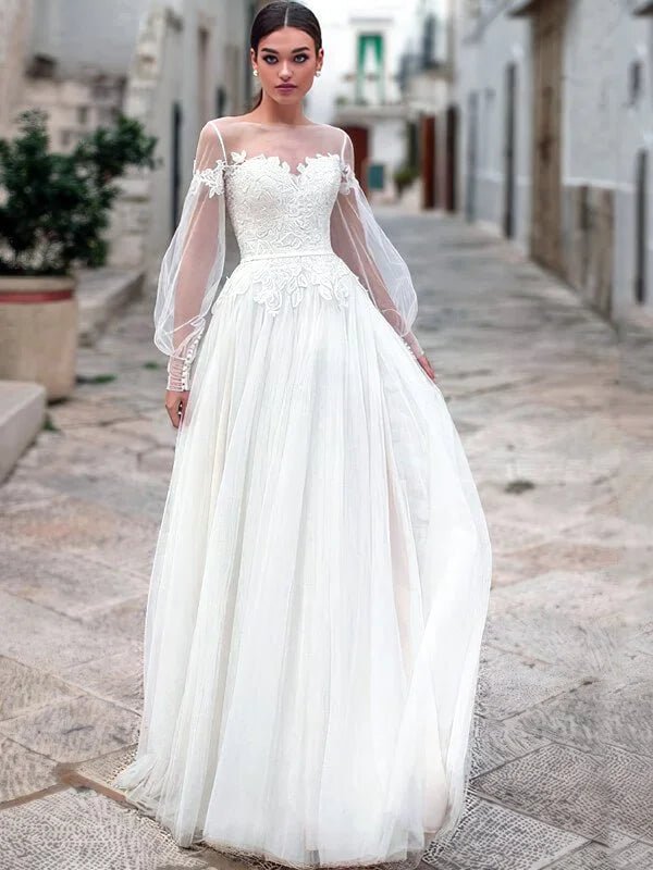 Robe de mariée bohème champêtre en tulle fluide avec manches longues transparentes et broderies florales, coupe princesse élégante, style romantique et naturel en extérieur.