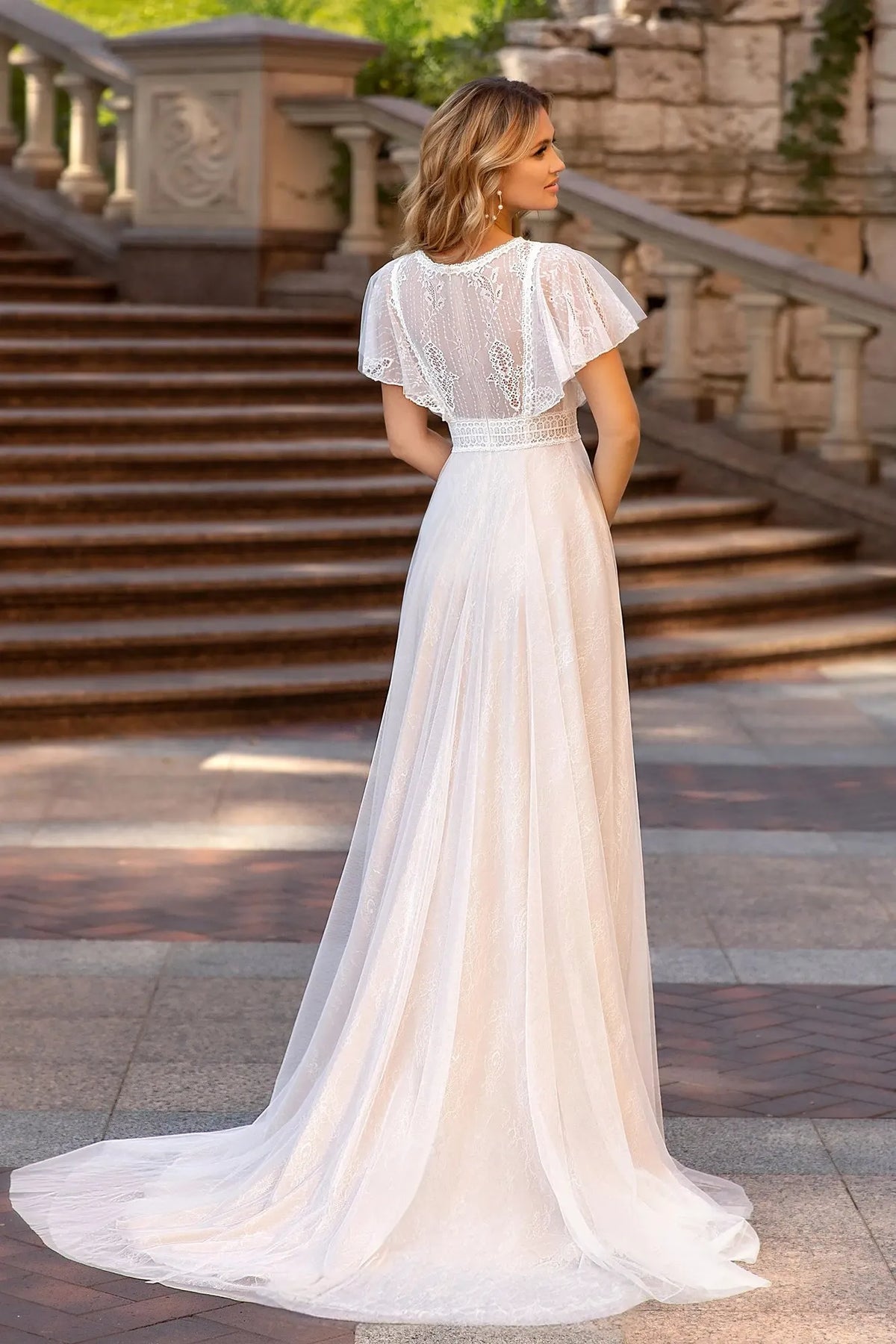 Robe de mariée empire bohème vue de dos, dentelle transparente, manches papillon et longue traîne en tulle
