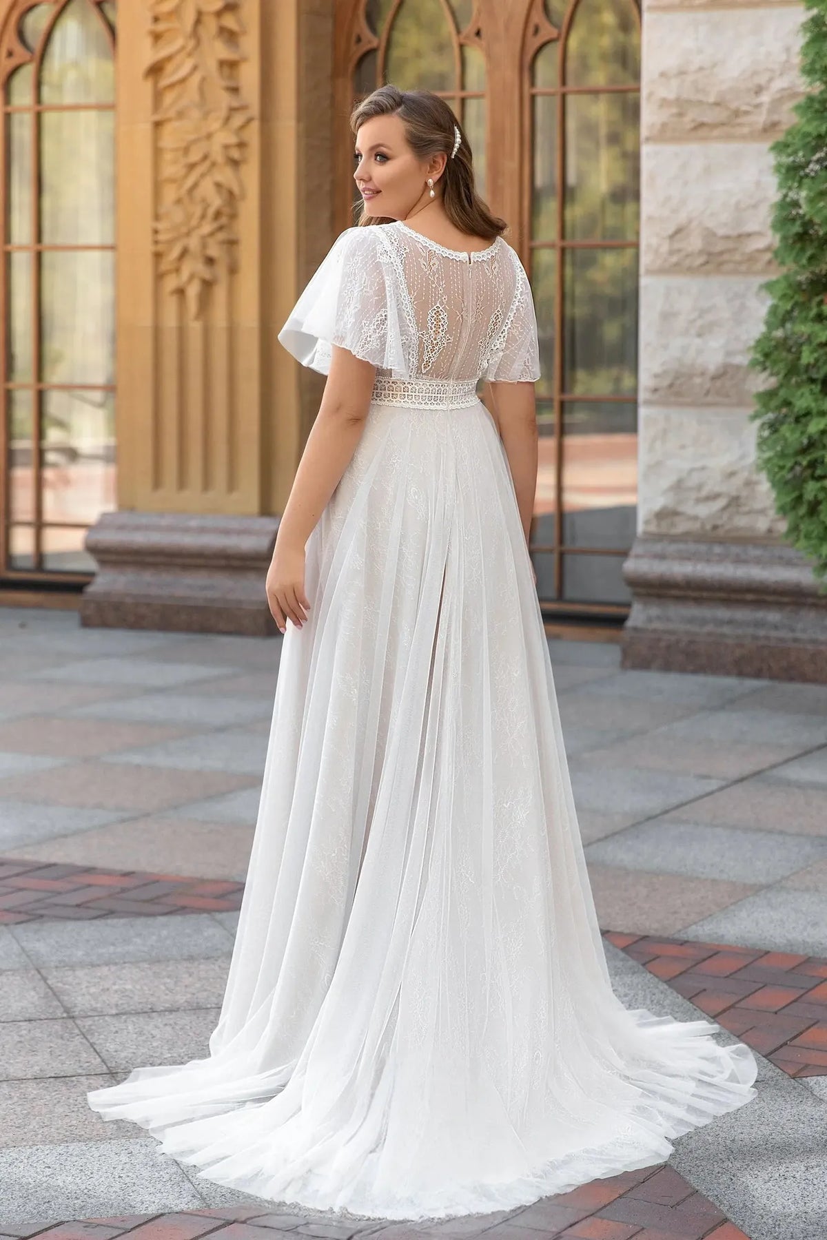 Robe de mariée empire grande taille vue de dos, dos transparent en dentelle, manches papillon en tulle et traîne fluide