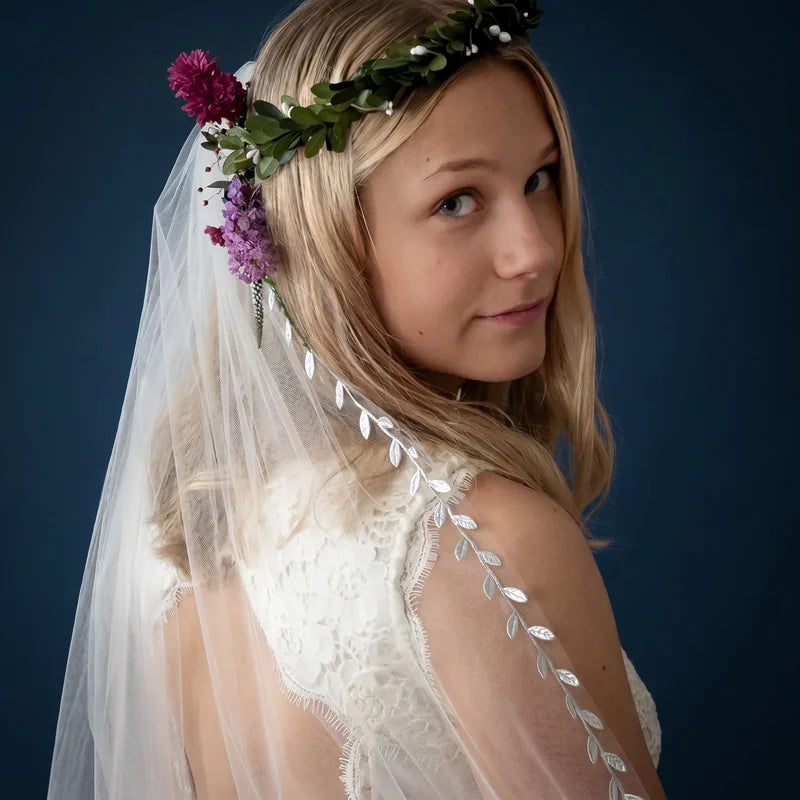 Mariée de dos portant un voile à bordure feuillage et couronne florale