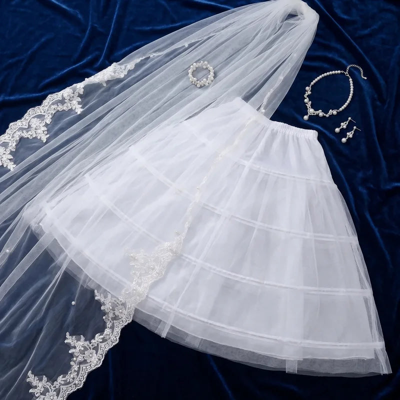 Voile de mariée en dentelle présenté avec jupon et bijoux perles assortis